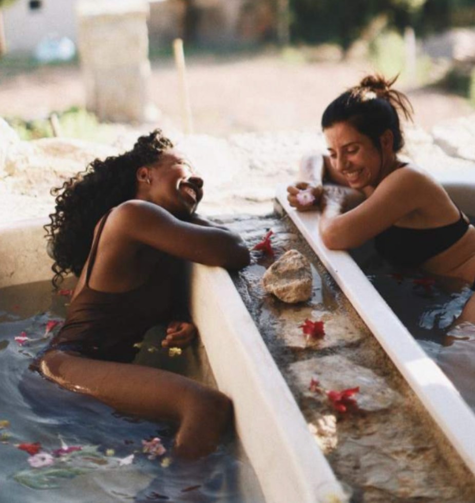 Two guests relaxing with drinks in the outdoor stone hot tub