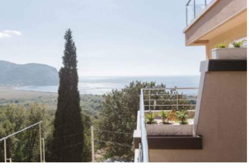 Balcony view over cypress trees toward the sea and mountains