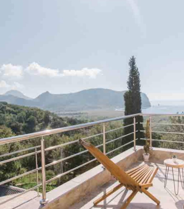 Wooden deck chairs on a terrace looking out over the mountains and the sea